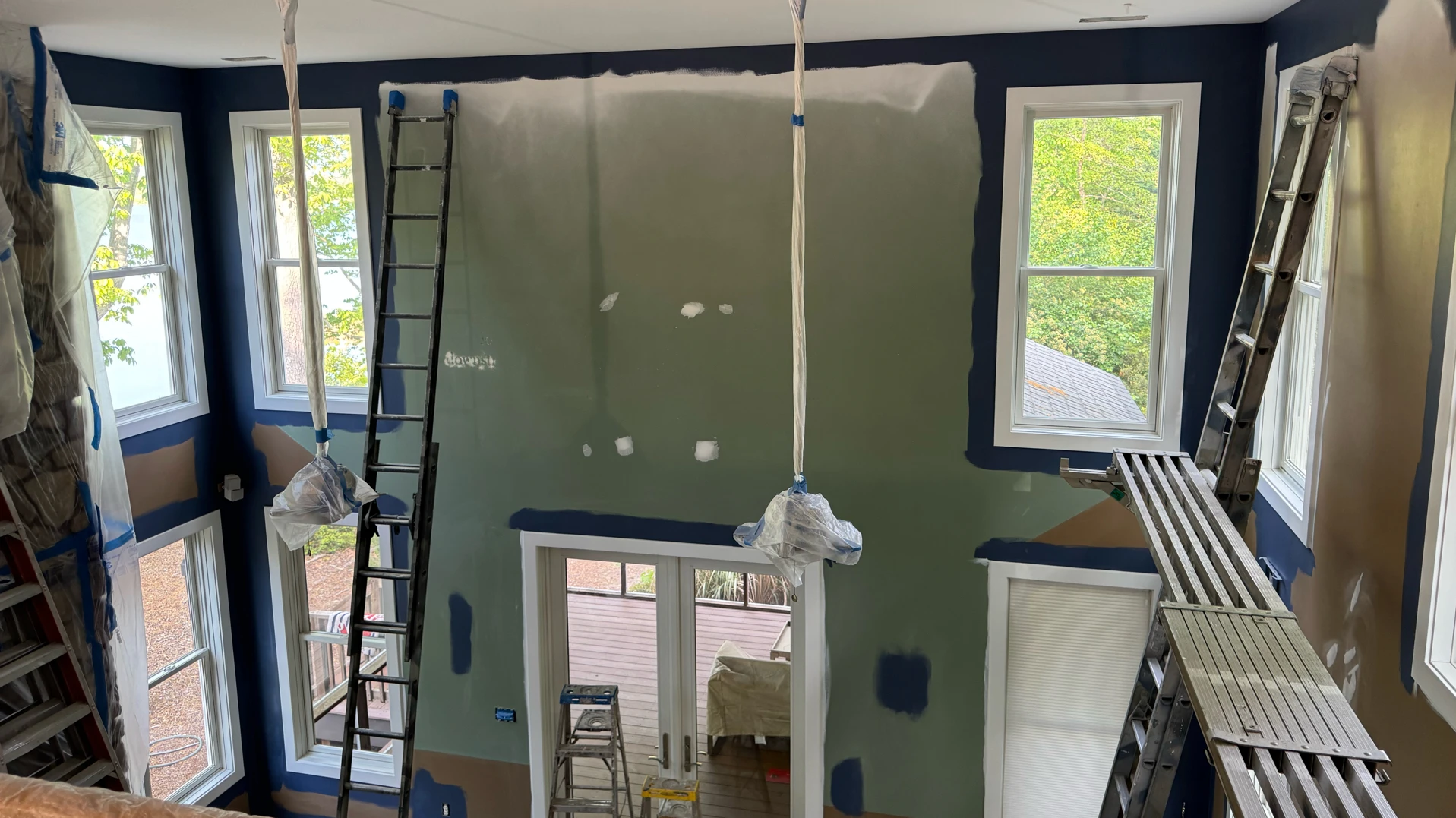 An interior wall is half painted dark blue with a patch of green and white, showing renovation in progress.